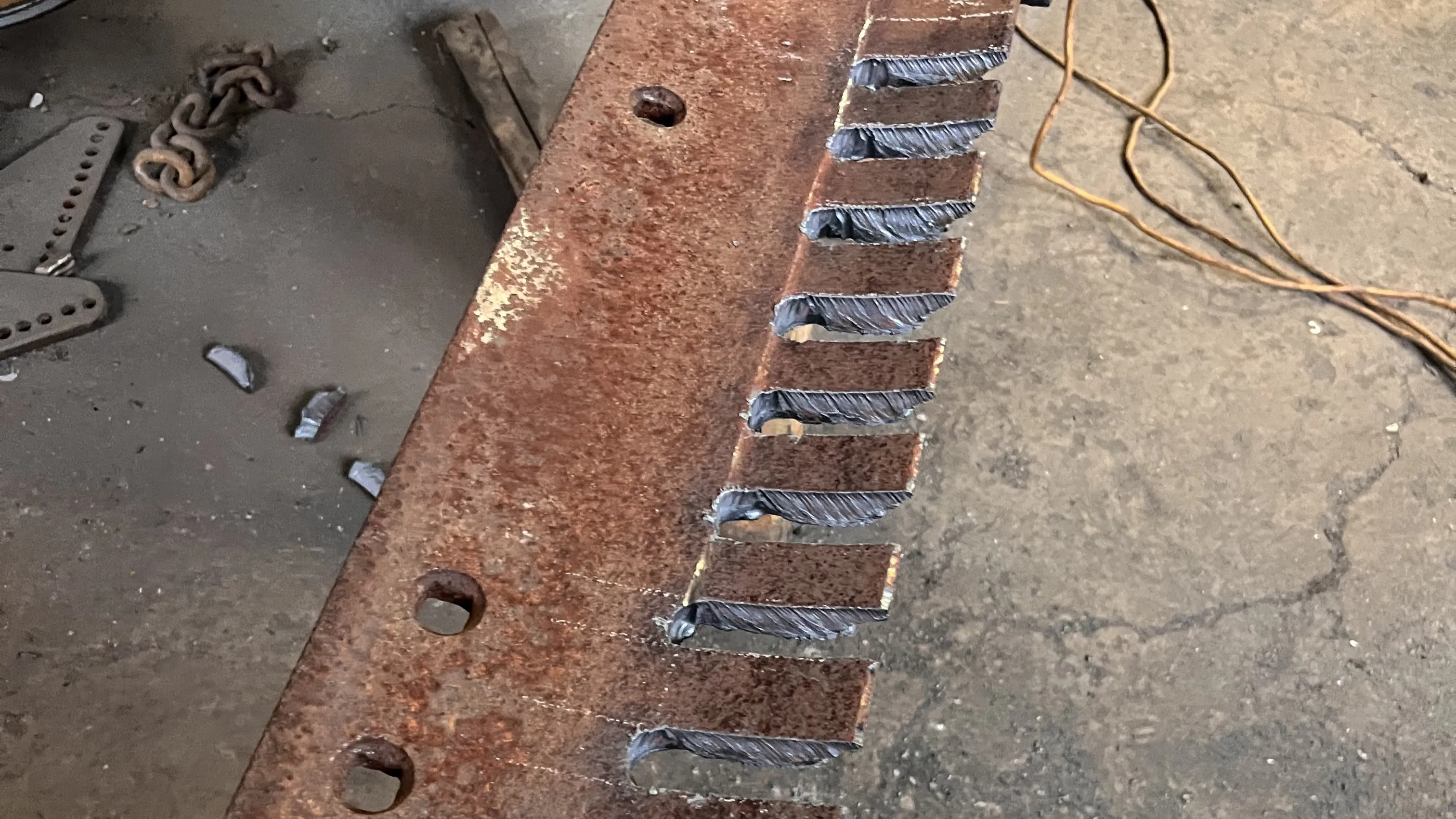 An image of a grader blade with notches cut into it.